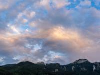 Leicht orange leuchtende Wolkenhaufen am Abendhimmel über Kampenwand und Scheibenwand
